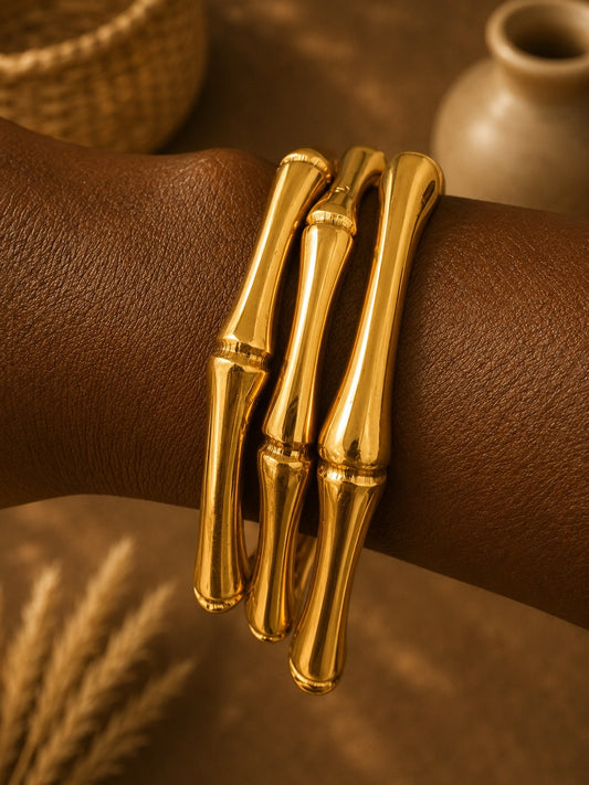 brass bamboo-style bracelets on a wrist with a blurred background