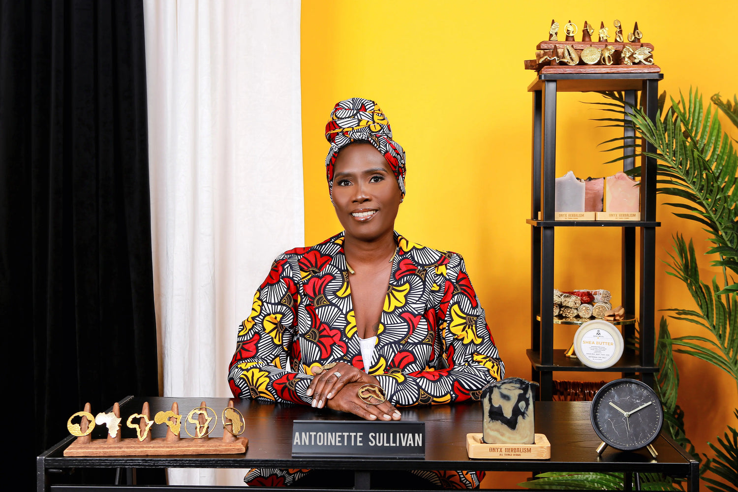 lady sitting at a desk in a suit jacket with matching ankara head wrap.