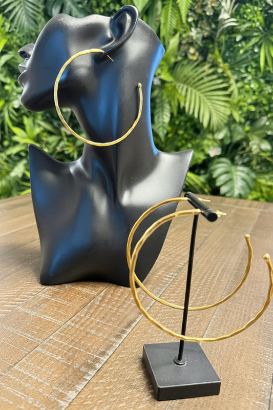 Brass  hoop earrings on a black mannequin head and stand.
