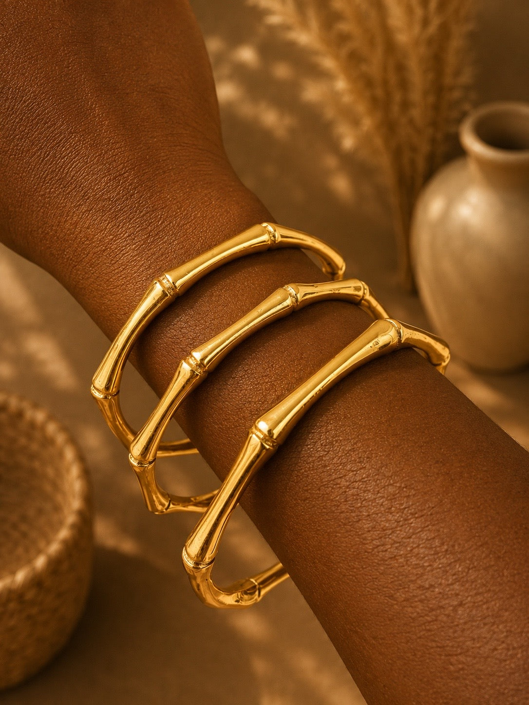 brass bamboo-style bracelets on a wrist with a blurred background