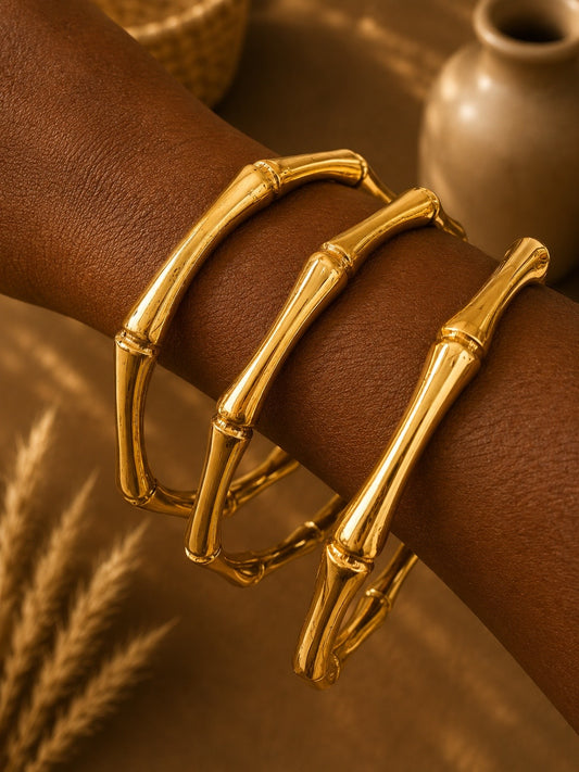 brass bamboo style bracelets on a wrist with a blurred background