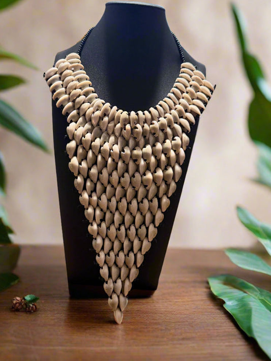 cowrie shell  necklace on a black mannequin against a blurred green leafy background